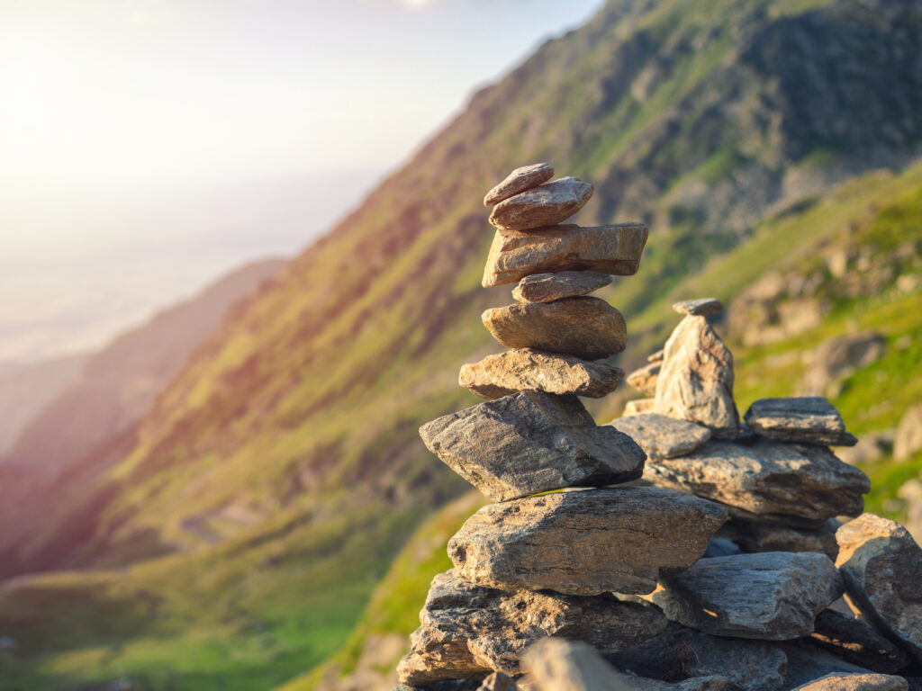 Stone stack with balanced stones on blurred mountain background in sunset warm light